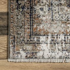 an area rug on a wooden floor with a brown, blue and white color scheme