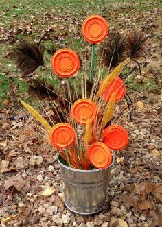 there are many orange flowers in a bucket on the ground with leaves and grass around it