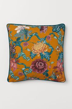 an orange floral pillow on a white background