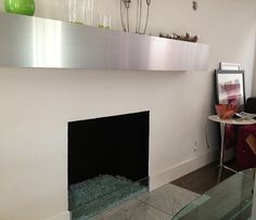 a living room with a fire place next to a glass table and vases on the wall