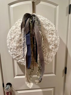 a white wreath with ribbons hanging from it's side on a door handle,