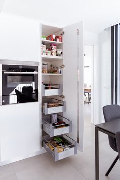 an open pantry in the corner of a room with a table and chairs next to it