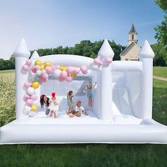 an inflatable bounce house with kids on it and balloons all around the outside