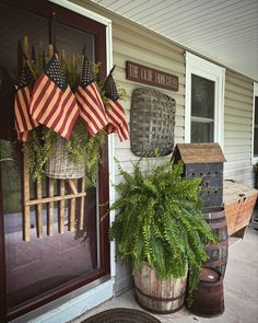 an american flag hanging on the front door of a house with potted plants in it