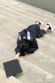 a person laying on the ground with a graduation cap