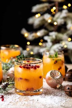 two glasses filled with orange liquid and garnished with cranberries on a table