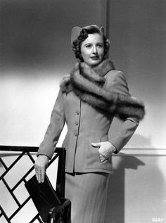 an old black and white photo of a woman in a suit with a fur collar