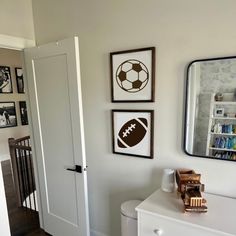 a room with pictures on the wall and a dresser in front of it, along with a mirror