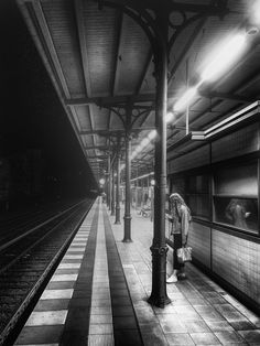 black and white photograph of a woman waiting at a train station