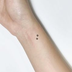 a person's arm with a small paw tattoo on the left side of their wrist