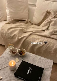 a white couch sitting next to a table with a book and some candles on it