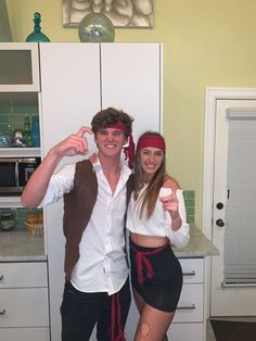 a man and woman dressed up in pirate costumes posing for a photo with their thumbs up