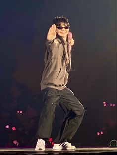 a man standing on top of a stage with his hands in the air and wearing sunglasses