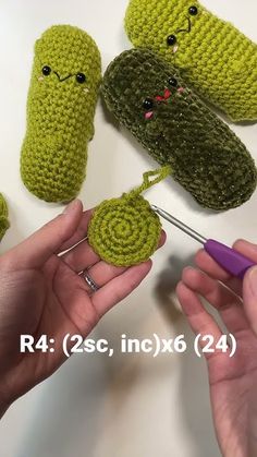 crocheted items are being displayed on a table with two hands holding the yarn