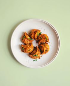 a white plate topped with dumplings on top of a green table