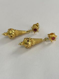 22K gold Etuscan style drop earrings with rubies top. The earrings measure 1 1/4 inches total length and about 1/4 inch wide at their widest. The earrings are not stamped so the gold quality has been determined by acid testing. The earring backs are 18K and stamped. Please note, the rubies are very included and slightly different in color ( see photos) Gold Ruby Earrings, Pierced, Yellow Gold Ruby Earrings Hallmarked, Ruby Earrings With Intricate Design In Yellow Gold, Gold Ruby Earrings For Formal Occasions, Yellow Gold Ruby Earrings With Intricate Design, Formal Gold Ruby Earrings, Gold Ruby Temple Jewelry Earrings, Temple Jewelry Style Ruby Earrings In Yellow Gold, Gold Ruby Earrings With Latkans