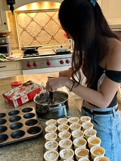 a woman is making cupcakes in the kitchen