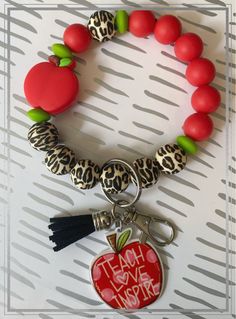 a bracelet with an apple and tassel on it