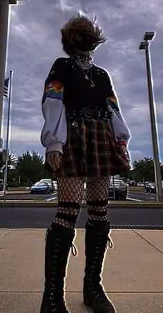 a woman standing in front of a pole with her hair blowing in the wind and wearing knee high boots