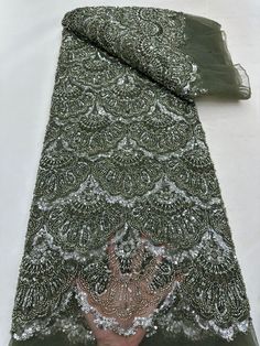 a person's hand on top of a piece of green cloth with silver sequins