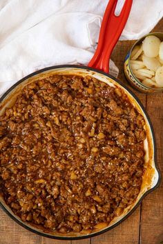 a pie sitting on top of a wooden table next to a red handled spatula