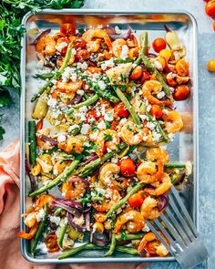 a tray filled with shrimp, asparagus and tomatoes on top of a table