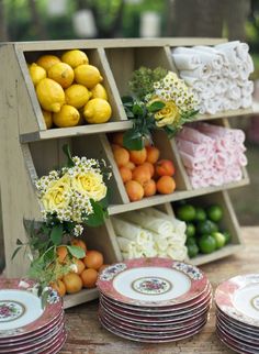 there are many plates on the table with lemons and oranges in boxes next to each other