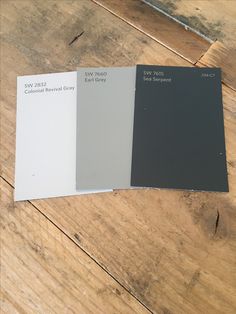 three different shades of paint sitting on top of a wooden floor