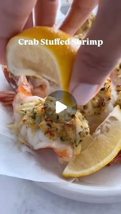 a person is dipping some food into a plate with lemon wedges and shrimp on it