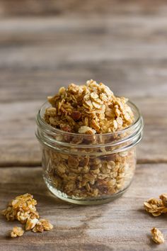 a glass jar filled with granola on top of a wooden table