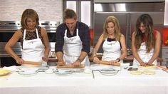 three women and two men are in the kitchen preparing food