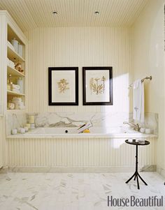 a bathroom with two framed pictures on the wall and a bathtub in the corner