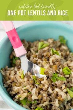 a blue bowl filled with brown rice and green onions, topped with a pink spoon