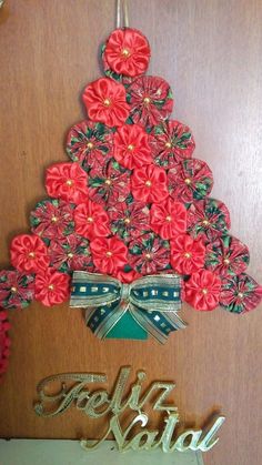 a christmas tree made out of red flowers on top of a wooden door with the word holiday written below it