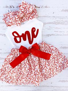 a red and white dress with the word one printed on it, tied to a wooden background