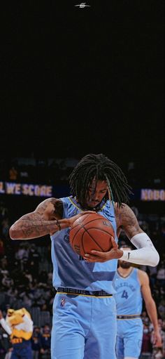 a man with dreadlocks holding a basketball in front of other men on a court