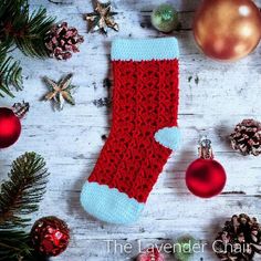 a red and blue knitted christmas stocking next to ornaments on a white wooden surface