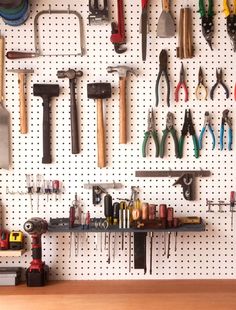 there are many tools hanging on the pegboard in this workbench area,