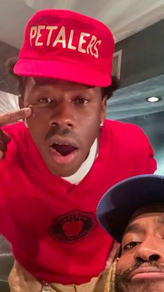 two men in red shirts and hats posing for the camera with one man wearing a red hat