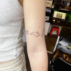 a woman with a tattoo on her arm that has two cats running across the screen