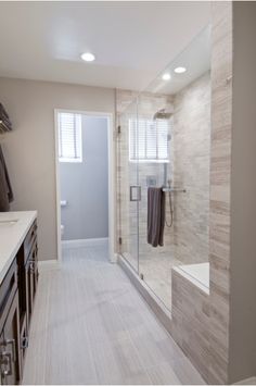 a walk in shower sitting next to a white sink and counter top under a window