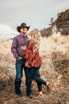 a man and woman are standing together in the middle of a field with tall grass