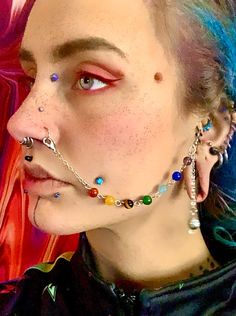 a woman with piercings on her nose and nose chain in front of a colorful background