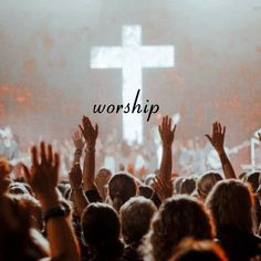 a group of people with their hands up in front of a cross on a stage