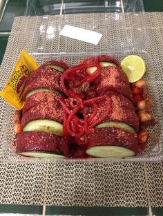 a tray with sliced cucumbers, strawberries and lemon wedges on it