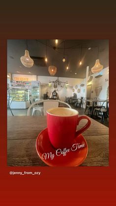 a red coffee cup sitting on top of a saucer next to a wooden table