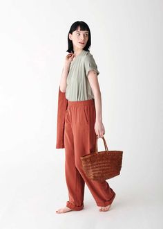 a woman is holding a basket and standing in front of a white wall with her hands on her hips