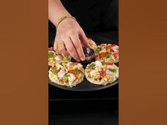 a person is cutting into small pizzas on a black plate with a brown background