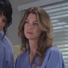 two women in scrubs standing next to each other with one looking at the camera