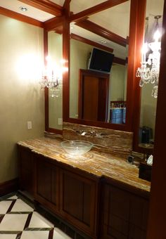 a bathroom with a marble counter top next to a large mirror and chandelier